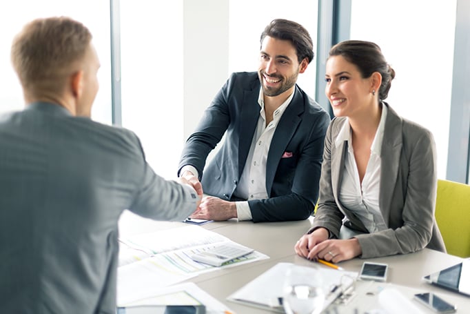 A man reviewing insurance options with a couple sitting at a table.