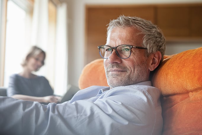 Man with glasses laying on an orange couch