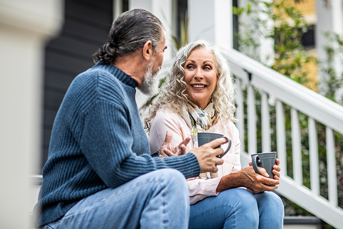 Older man and woman chatting and sitting on a porch