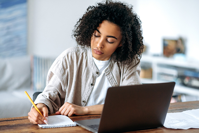 Woman writing down information from her laptop