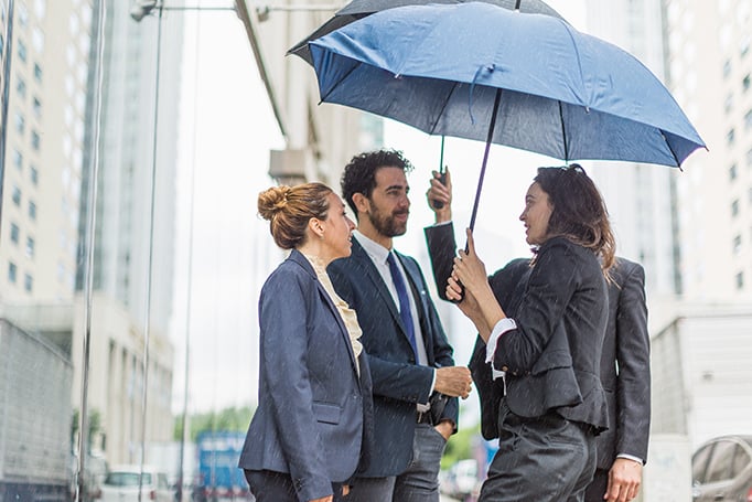 Group of businesspeople talking under umbrellas