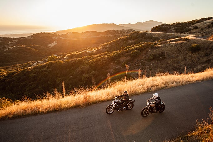 Two motorcyclists driving in the sunset