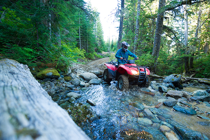 Man riding ATV over a rocky stream